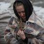 Egy helyi lakos egy macskát visz a kabátjában, amelyet egy orosz rakétatámadásban megsemmisült lakóépületben találtak a Kijev melletti Vishorod városában 2022. november 24-én