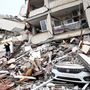 Egy összedőlt épület és egy megrongálódott jármű a 7,7-es erősségű földrengés után Törökországban 2023. február 6-án