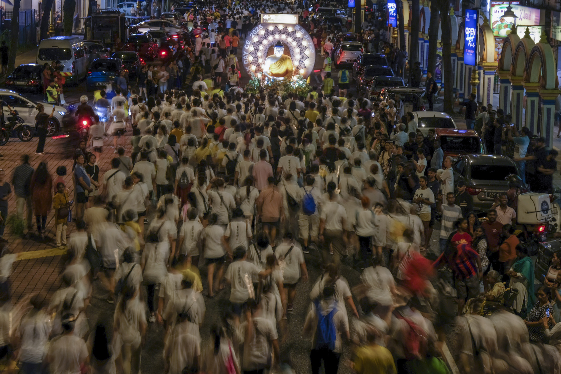 Buddhista hívők követik a kocsik felvonulását a Vesak-napi felvonulások során Malajziában 2025. május 12-én