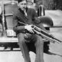 Clyde Barrow puskával pózol egy autó előtt.