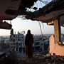 Egy palesztin nő az otthonai romjaiból figyeli a naplementét