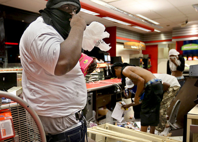 Könnygázgránátot dob vissza  rendőröknek egy tüntető Fergusonban.