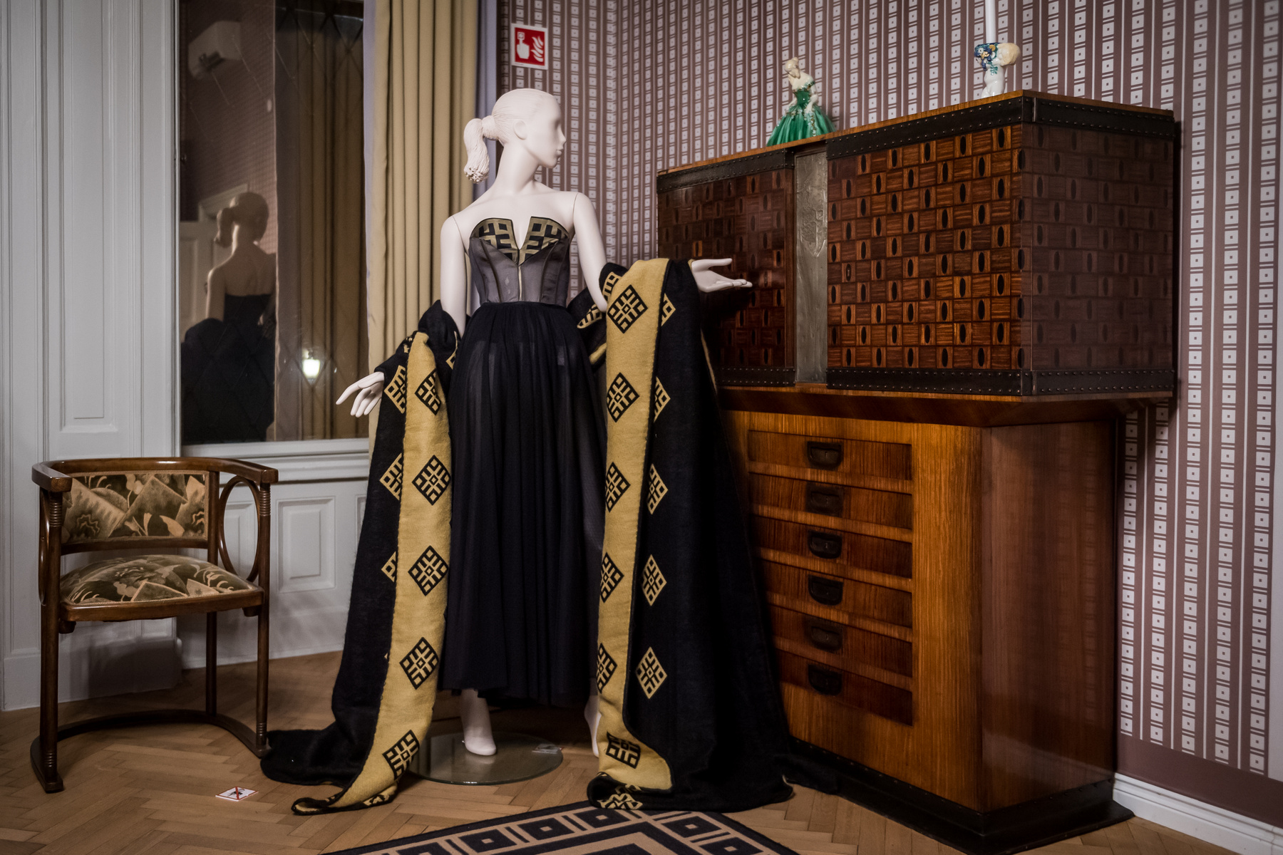 Az időszaki kiállításon megjelenő öltözékek színvilága az arany és a fekete. A kalitka motívuma XVIII. századi bútorintarziáról származik