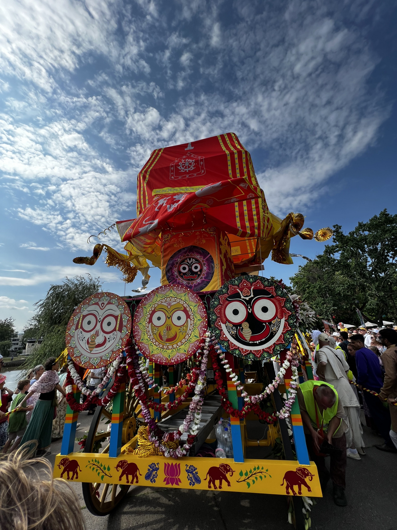 A szekér előtt táncosok, énekesek, valamint egy Krisna-völgyi ökrösszekér halad.