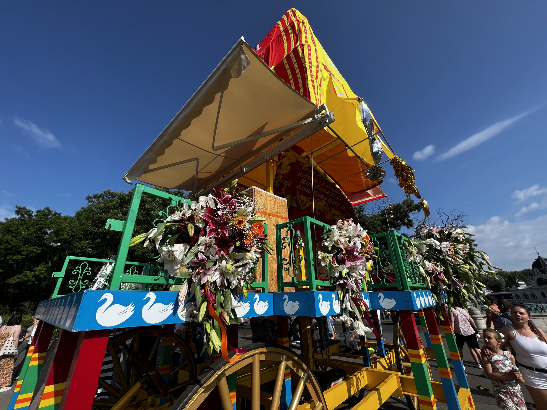 A szekér előtt táncosok, énekesek, valamint egy Krisna-völgyi ökrösszekér halad.