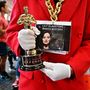 Egy Oscar-rajongó egy Oscar-díj másolattal mutatja a legjobb filmnek járó díjat 2024. március 8-án