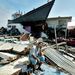 Egy férfi egykori háza romjain Aceh tartomány székhelyén, Banda Acehben. Az akár 30 méter magas hullámokkal ez a cunami minden idők egyik legsúlyosabb természeti katasztrófája volt. A katasztrófa után több mint 7 milliárd dollár értékű segély áramlott a térségbe a világ országaiból, azonban ezek szétosztása csak nehezen indult be.