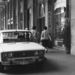 1980-ban az egyik közép-felső kategóriás gépkocsinak számított a Lada 1600-os. Gyakran vállalati autónak használták, és a mindenható igazgató elvtárs sofőrje sok mindent megengedhetett magának, csak úgy, mint a kor kisvállalkozójának számító gazdag maszek, akik körében szintén divatos volt a szocialista BMW-nek is nevezhető márka. A képen sejthetően az Elixír illatszerbe ugrott be a kocsi gazdája, a lehető legpöffeszkedőbb módon parkolva. Méghozzá pont annak a Madách térnek az árkádjai alatt, ahol pár évvel azelőtt megjelent az első pesti parkolóautomata.