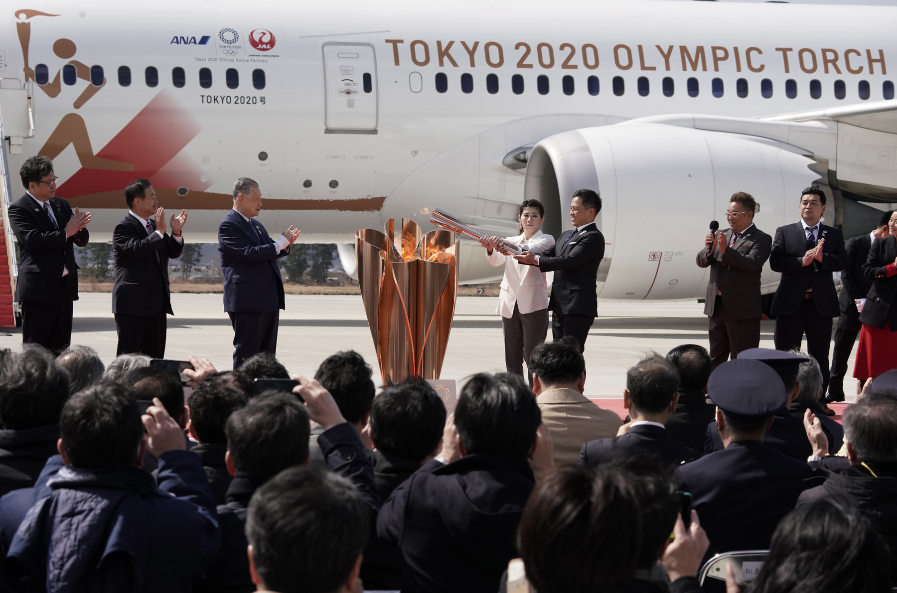 A japán légierõ Kék Impulzus műrepülőcsoportja az olimpiai színeket festi fel kondenzcsíkokkal az égre az ünnepségen amellyel a 2020-as tokiói nyári olimpiára Görögországból Japánba érkezõ lángot fogadják a japán légierő higasimacusimai támaszpontján 2020. március 20-án. 