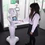Egy látogató kezet fog Pepperrel a japán Softbank távközlési konszern humanoid robotjával