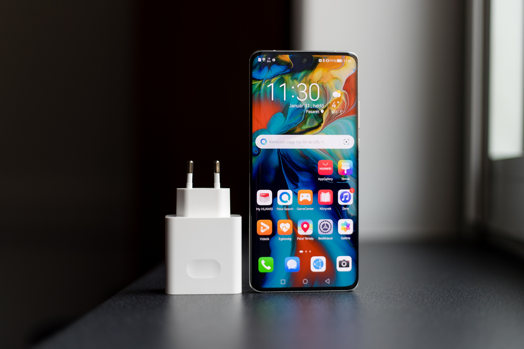 A telefon alja és teteje sík, így akár megáll saját lábán is. A fali adapter hatalmas.