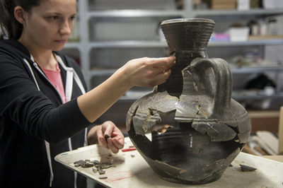 Skriba-Nagy Mónika régész egy vágott malomkövet vizsgál Kecskeméten a Katona József Múzeumban